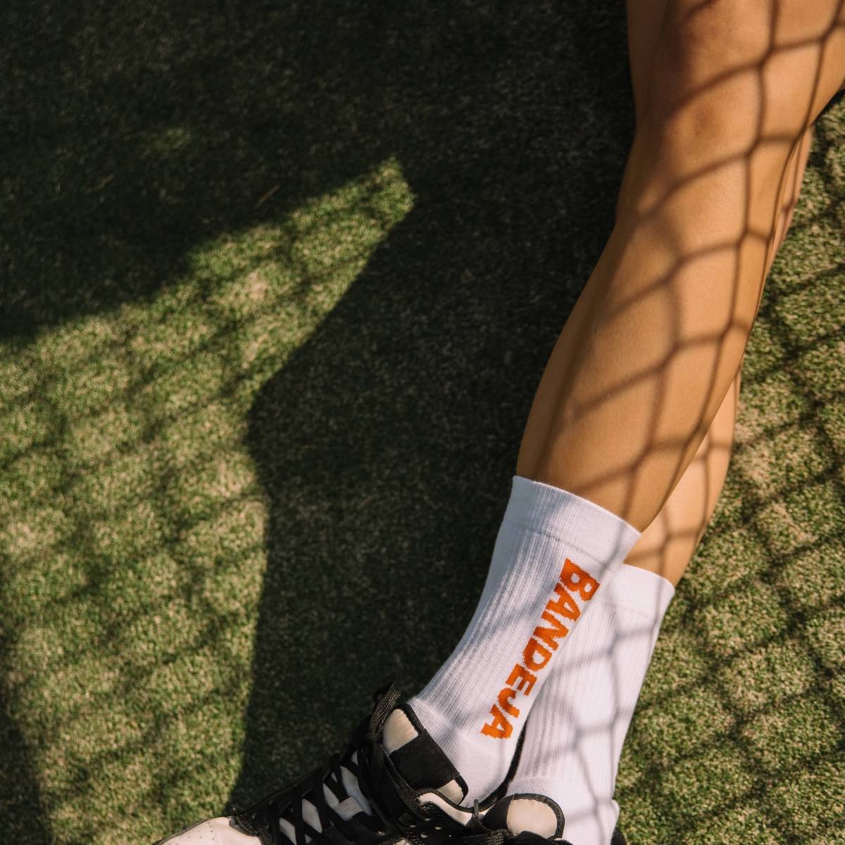Model wearing Cuera 2-pack Bandeja Padel Socks in White/Orange, close-up detail on model