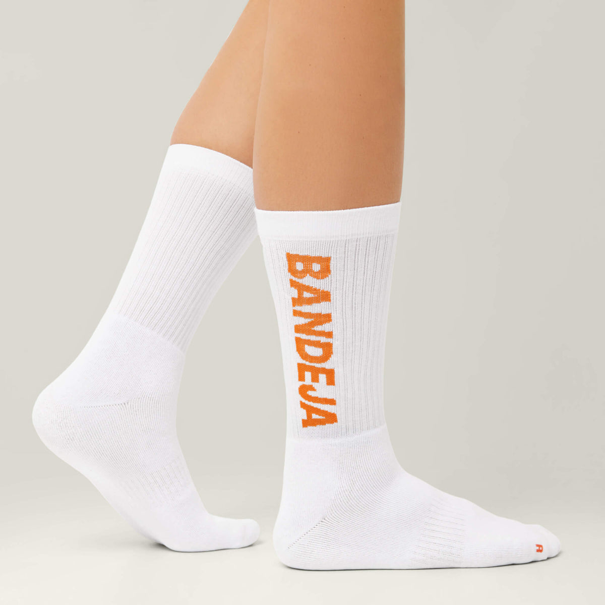 Model wearing Cuera 2-pack Bandeja Padel Socks in White/Orange, front studio view