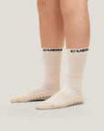 Model wearing Cuera 2-Pack Grip Socks in Sand, back studio view