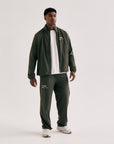 Model wearing Cuera Active Cuera Track Pants in Army, back studio view