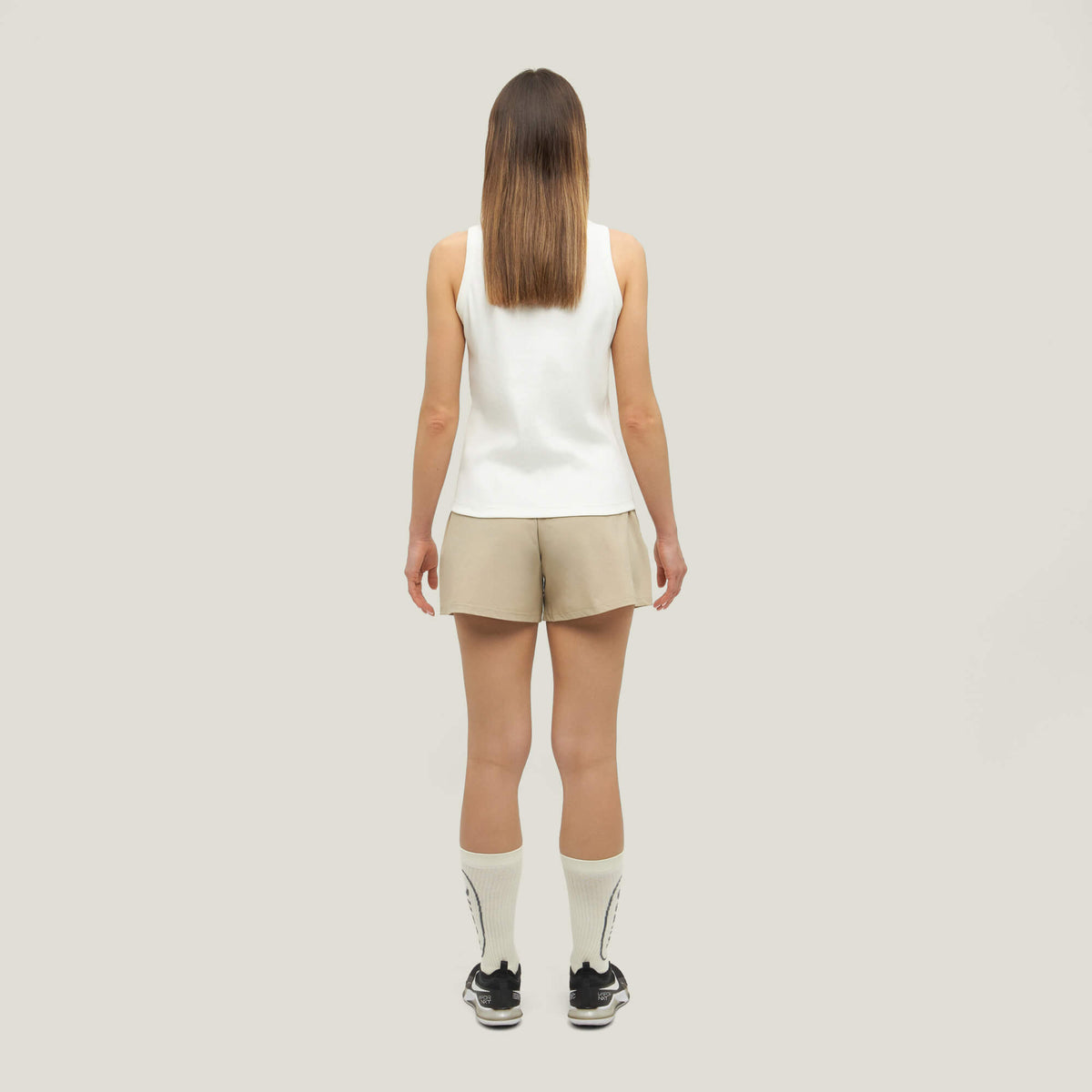 Woman wearing Cuera Womens Active Globe Shorts in Sand, back studio view