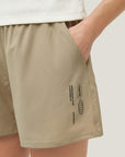 Woman wearing Cuera Womens Active Globe Shorts in Sand, close-up detail on model