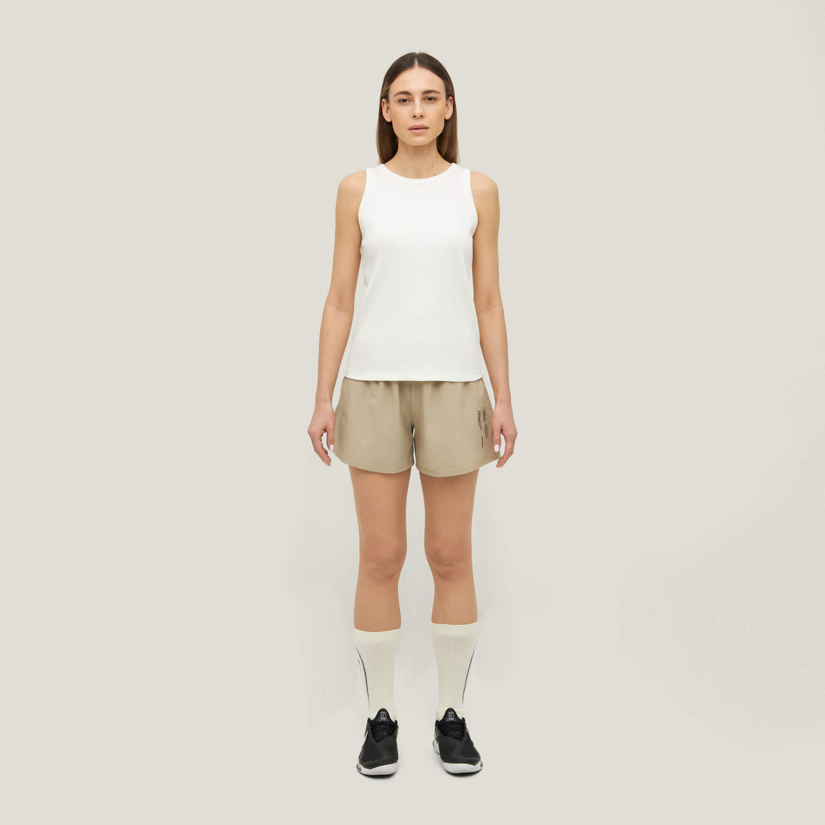 Woman wearing Cuera Womens Active Globe Shorts in Sand, front studio view