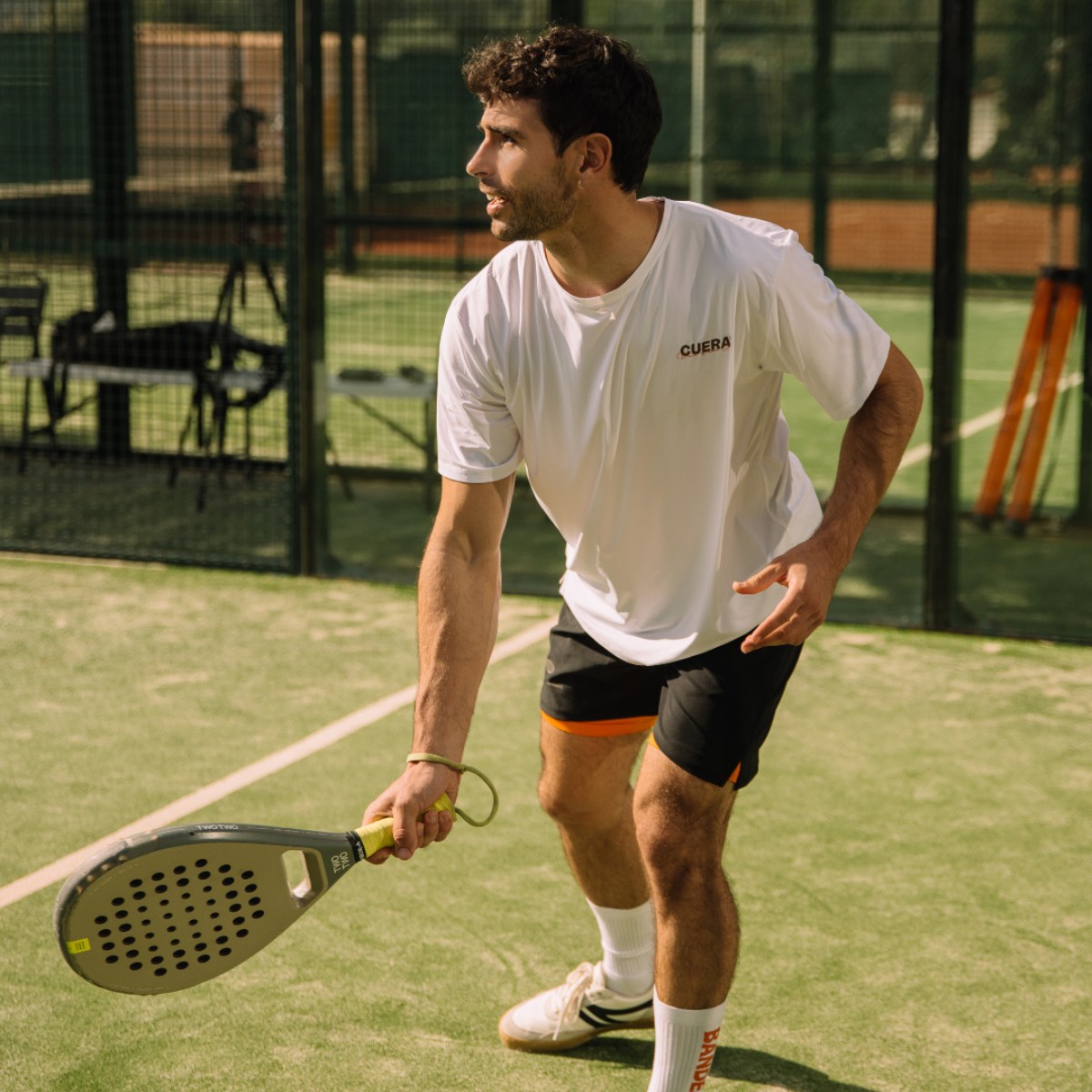Model wearing Cuera Active Light Weight T-Shirt in White, lifestyle action shot on the padel court