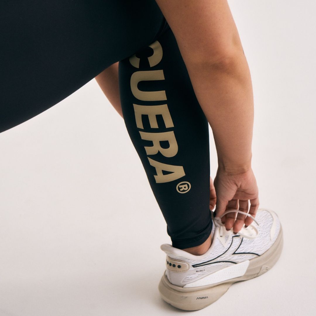 Model wearing Cuera Active Logo Tights Long in Black, close-up detail on model