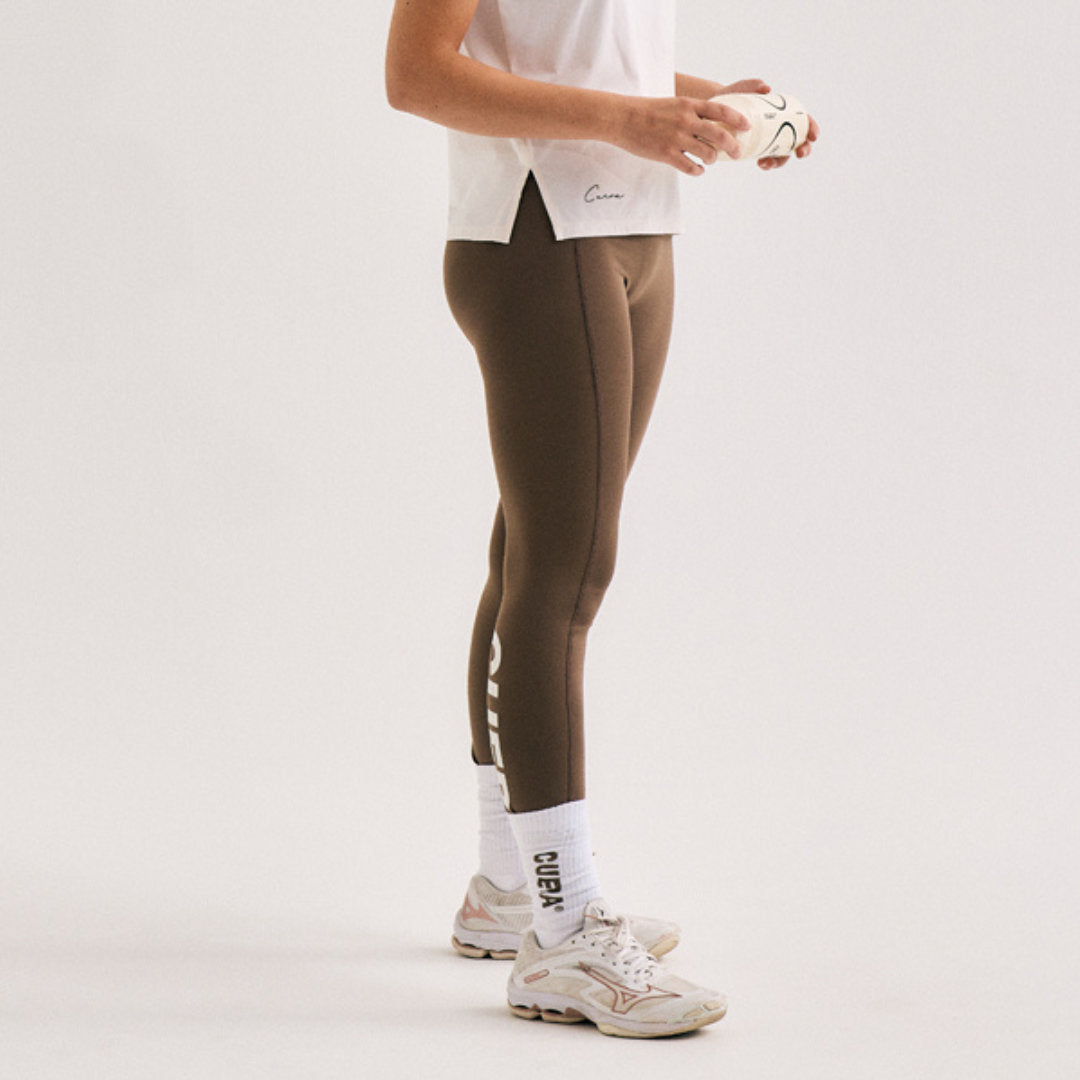 Model wearing Cuera Active Logo Tights Long in Walnut, close-up detail on model