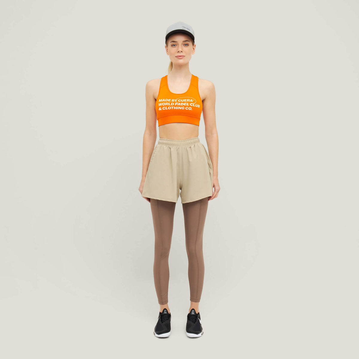 Woman wearing Cuera Active Made Bra in Orange with matching shorts, front studio view