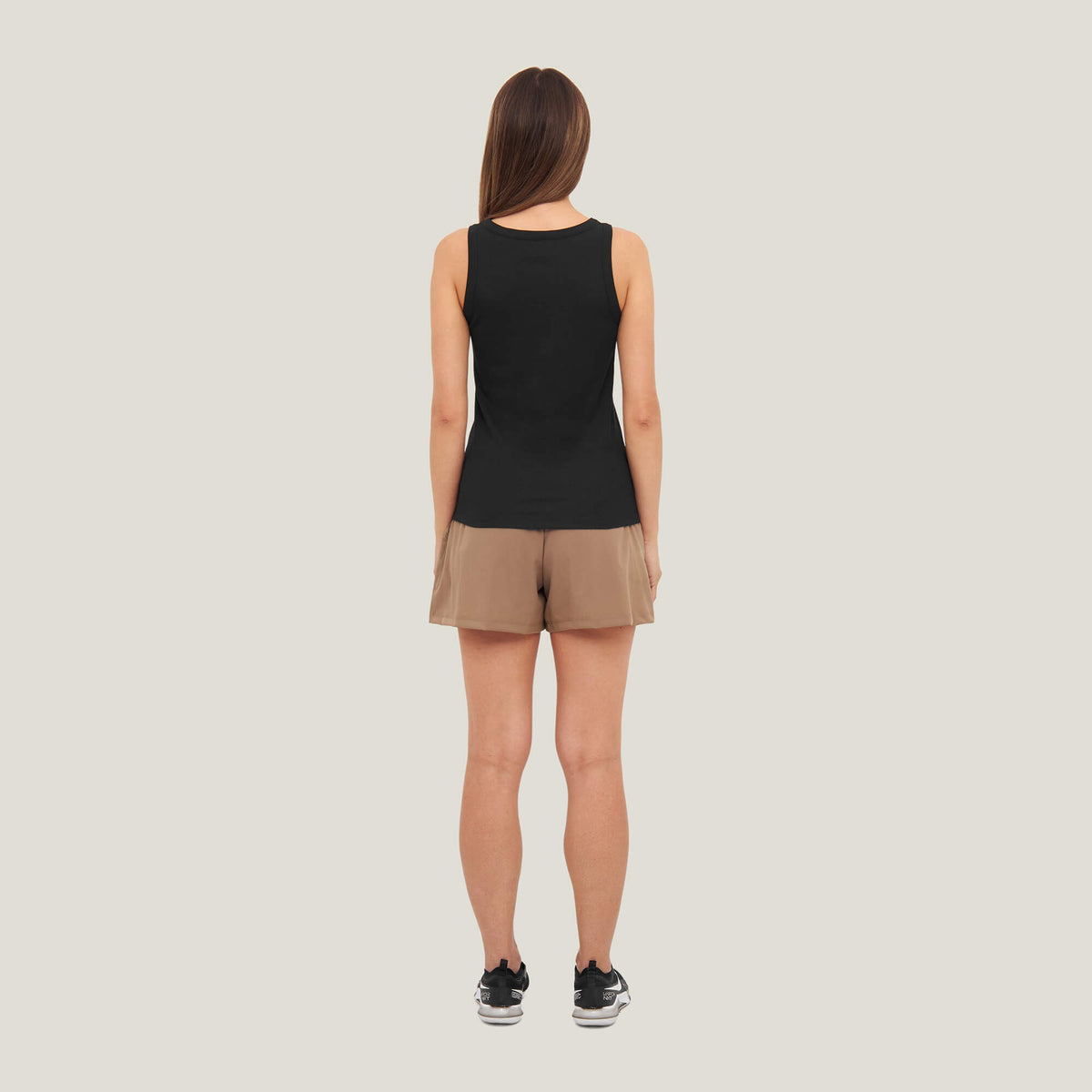 Model wearing Cuera Active Rib Tank Top in Black, back studio view