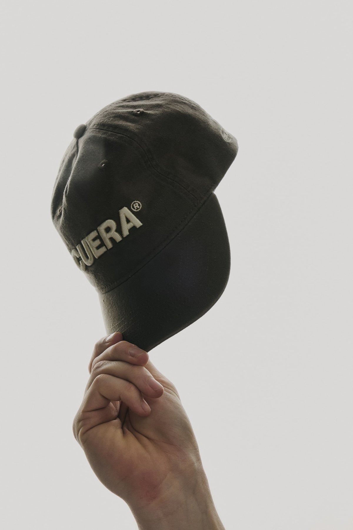 Model wearing Cuera Offcourt Cuera Cap in Antrasit, lifestyle action shot on the padel court