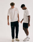 Model wearing Cuera Offcourt Logo T-Shirt in Off White w. Black, lifestyle action shot on the padel court