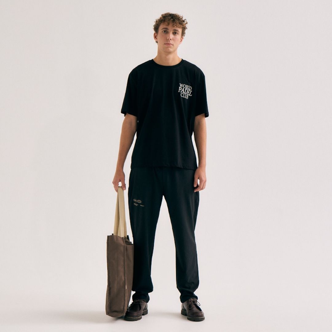 Model wearing Cuera Offcourt WPC T-Shirt in Black, lifestyle action shot on the padel court