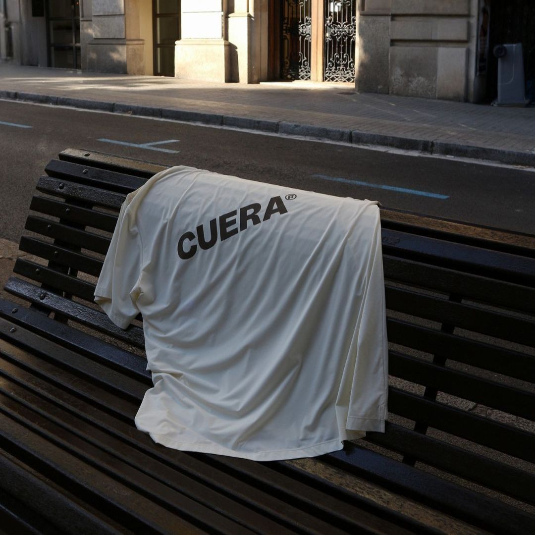 Model wearing Cuera Oncourt Airy Logo T-Shirt in Off White, lifestyle action shot on the padel court