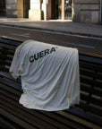 Model wearing Cuera Oncourt Airy Logo T-Shirt in Off White, lifestyle action shot on the padel court