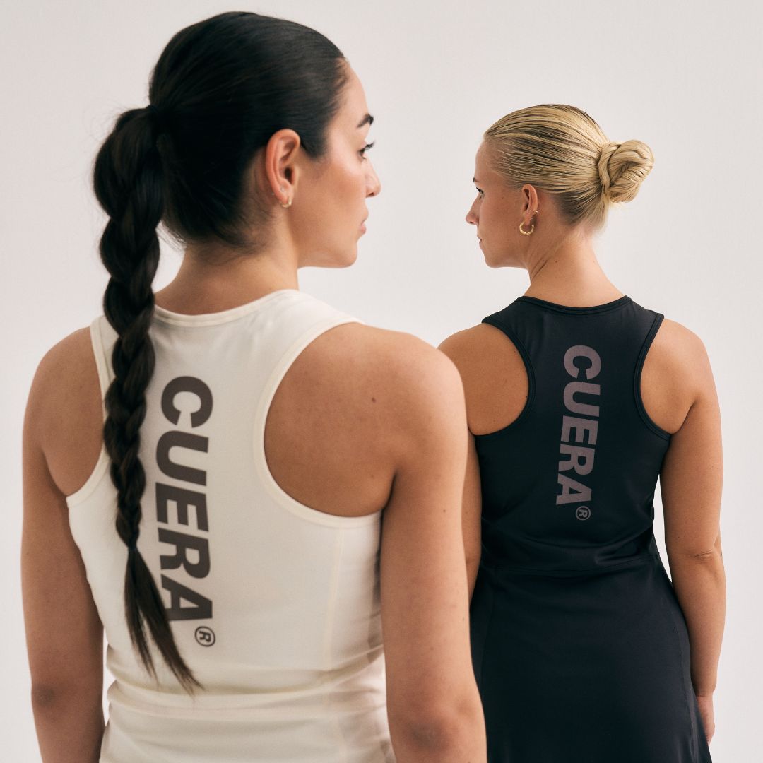 Model wearing Cuera Oncourt Cuera Dress in Black, lifestyle action shot on the padel court