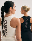 Model wearing Cuera Oncourt Cuera Dress in Black, lifestyle action shot on the padel court