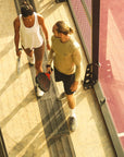 Model wearing Cuera Oncourt LS Layer T-Shirt in Sand, lifestyle action shot on the padel court