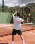 Model wearing Cuera Oncourt Made Polo ss in White, lifestyle action shot on the padel court