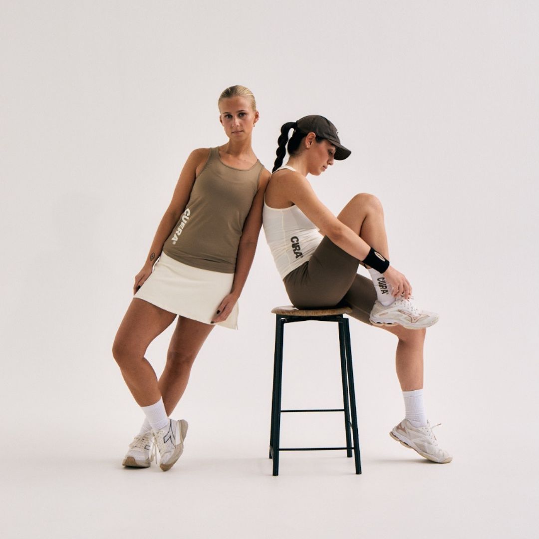 Model wearing Cuera Oncourt Slim Tank Top in Off White, lifestyle action shot on the padel court