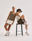 Model wearing Cuera Oncourt Slim Tank Top in Walnut, lifestyle action shot on the padel court