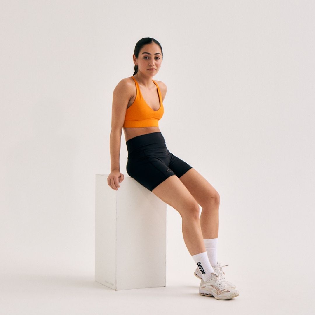 Model wearing Cuera Oncourt Soft Bra Top in Orange, front studio view