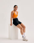 Model wearing Cuera Oncourt Soft Bra Top in Orange, front studio view