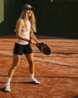 Woman playing padel in Cuera Women's Active Globe Shorts in Black on an outdoor court